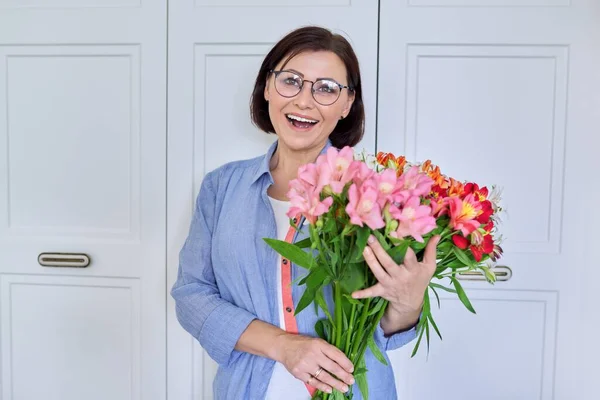 Porträtt av en medelålders leende kvinna med en bukett blommor — Stockfoto