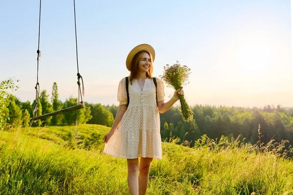 Šťastná usměvavá dospělá žena v šatech s kloboukem s kyticí divokých květin. — Stock fotografie