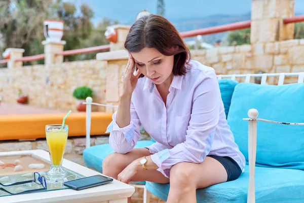 Triste chateado mulher madura sentado ao ar livre à mesa no café com smartphone — Fotografia de Stock