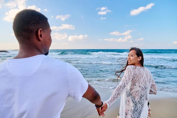 Amar feliz pareja caminando cogidos de la mano en la playa — Foto de Stock