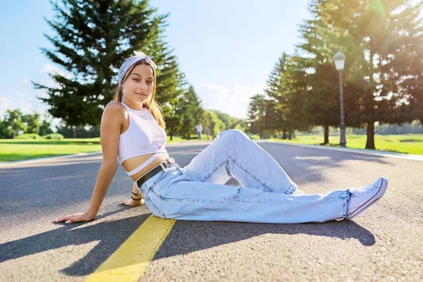 Menina adolescente na moda posando sentado na estrada no parque. — Fotografia de Stock
