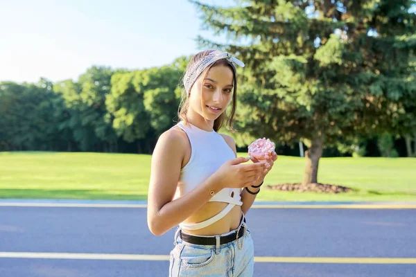 Retrato de menina adolescente alegre com bolo de donut, no parque de verão — Fotografia de Stock