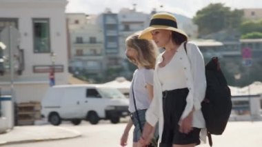 Anne ve küçük kızı birlikte yürüyorlar, el ele tutuşuyorlar.