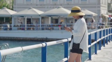 Şapkalı orta yaşlı bir turist akıllı telefon kullanarak selfie çekiyor.