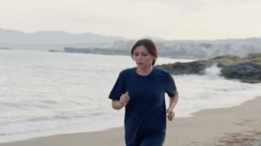 Sabahları kumsalda koşan orta yaşlı bir kadın..