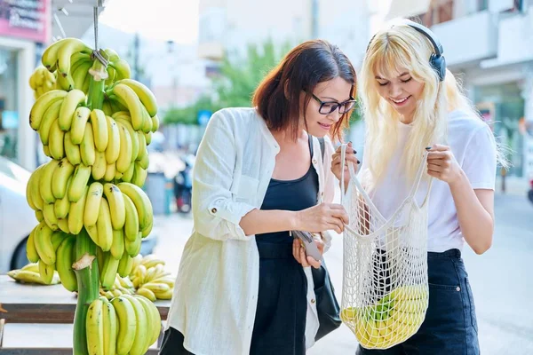 Mãe e filha adolescente comprando bananas em um mercado de varejo de rua — Fotografia de Stock