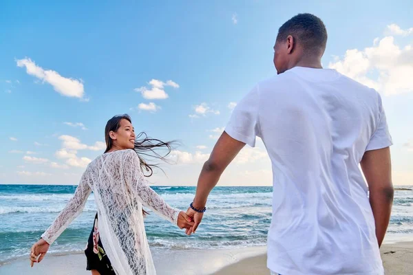 Houden van gelukkig paar lopen hand in hand op het strand — Stockfoto