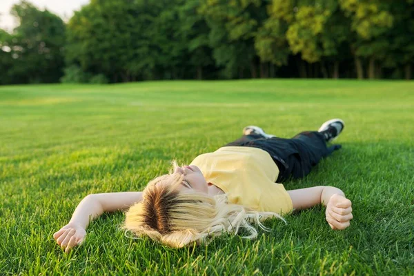 Young blonde woman lying on the grass in a summer park. — 图库照片