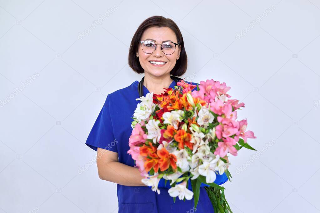 Woman doctor, nurse in blue with bouquet of flowers, on light background