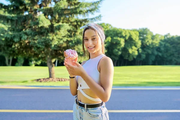 Retrato de menina adolescente alegre com bolo de donut, no parque de verão — Fotografia de Stock