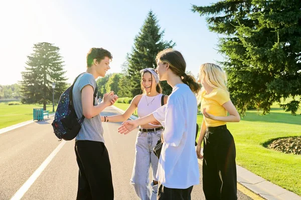 Encuentro de amigos adolescentes sonrientes en un soleado parque de verano — Foto de Stock