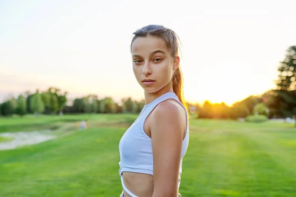 Serious teenage girl looking at the camera, in the park on lawn. — 스톡 사진