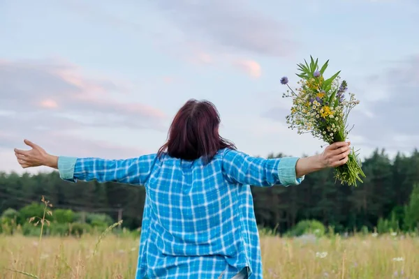 야생화 꽃다발을 들고 팔을 들고 있는 여인, 여름의 자연 — 스톡 사진