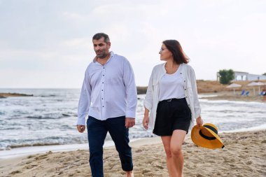 Kumsalda birlikte yürüyen mutlu orta yaşlı çift..