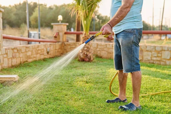 Man watering the lawn with a hose in the morning — Stock Photo, Image