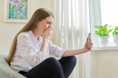 Akıllı telefon ekranına bakarak ağlayan genç bir kadın.