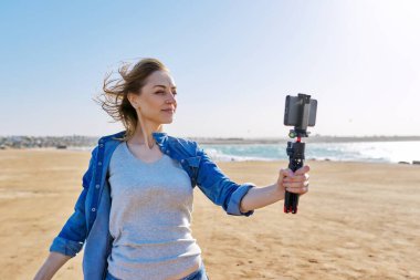 Olgun bir kadın akıllı telefondan video kaydediyor.