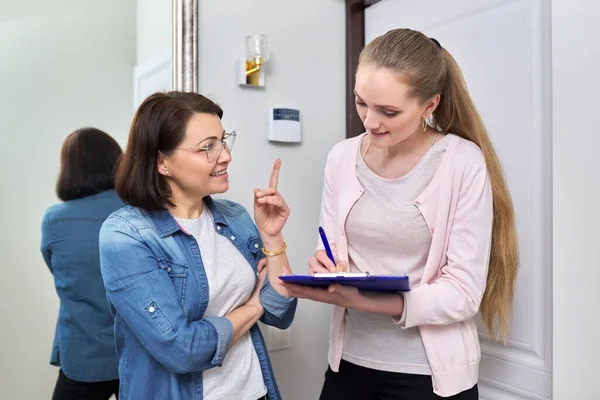 Female social worker talking to middle aged woman at home