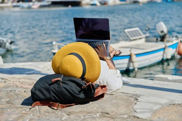 Mujer en sombrero escribiendo en el ordenador portátil, fondo del barco de la bahía de agua — Foto de Stock