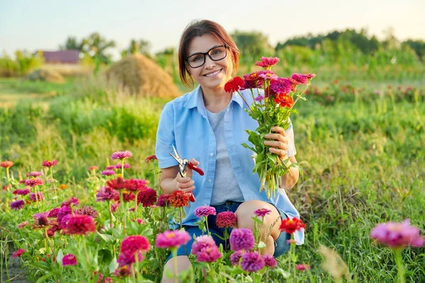 中年妇女微笑着，在花园里捧着一束新鲜的紫罗兰花 — 图库照片