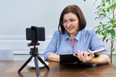 Kadın öğretmen, akıl hocası, psikolog akıllı telefonun webcam 'ine bakıyor, konuşuyor, danışmanlık yapıyor.