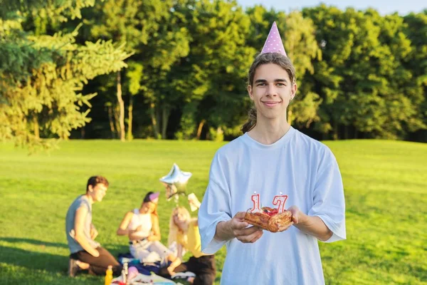 Glücklicher Typ Teenager mit Geburtstagsmütze und Kuchen mit Kerzen 17 — Stockfoto