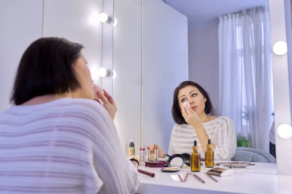 Belle femme d'âge moyen se maquillant devant un miroir. — Photo