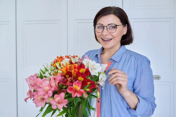 Mooie glimlachende vrouw van middelbare leeftijd met een boeket bloemen — Stockfoto