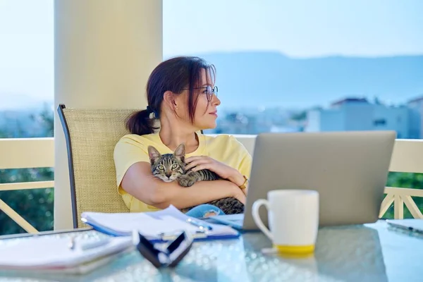 Домашнє робоче місце жіночий фрілансер, що працює дистанційно з домашнім котом на руках — стокове фото