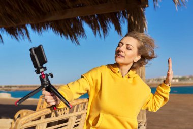 Sahilde konuşan orta yaşlı bir kadın akıllı telefon kullanıyor..