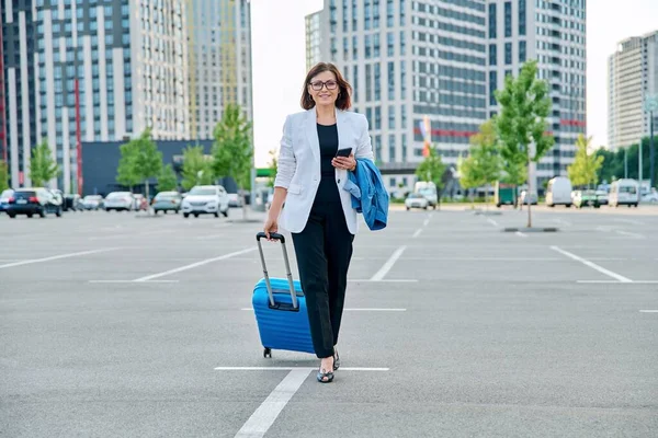 带着手提箱走路的成熟女商人，现代城市背景 — 图库照片