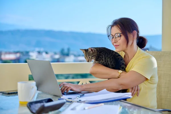 Casa di lavoro freelance femminile che lavora a distanza con gatto domestico tra le braccia — Foto Stock