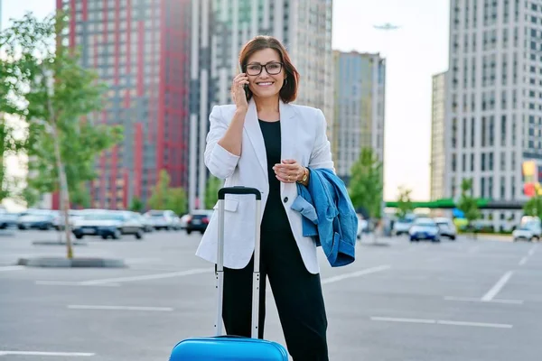 Ділова жінка середнього віку з валізою, міський фон . — стокове фото