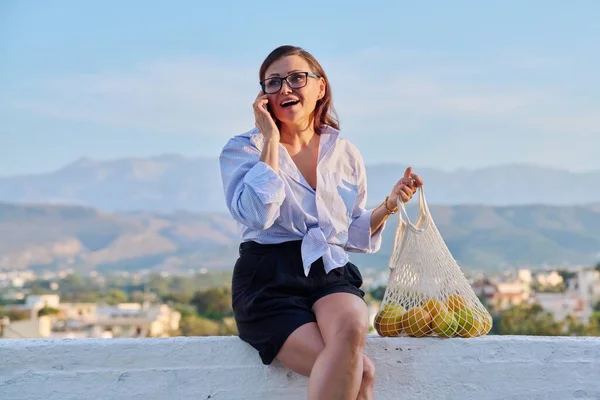 Feliz mulher de meia-idade falando no telefone móvel ao ar livre. — Fotografia de Stock