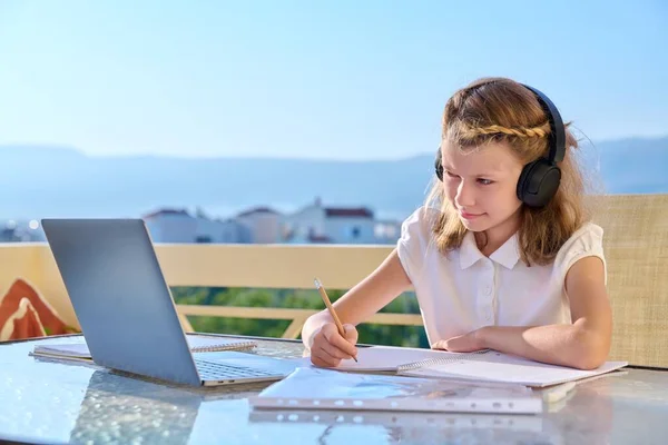 Ragazza bambino con le cuffie sta studiando utilizzando un computer portatile. — Foto Stock