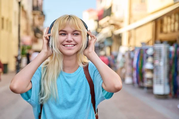 Jovem mulher em fones de ouvido com mochila na rua da cidade turística — Fotografia de Stock