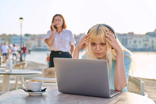 Surpreendido adolescente feminino com fones de ouvido olhando para laptop no café ao ar livre — Fotografia de Stock