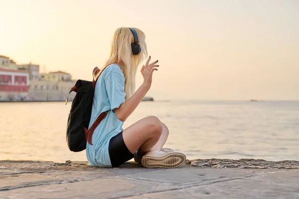 Mujer joven y feliz con mochila en auriculares escuchando música — Foto de Stock