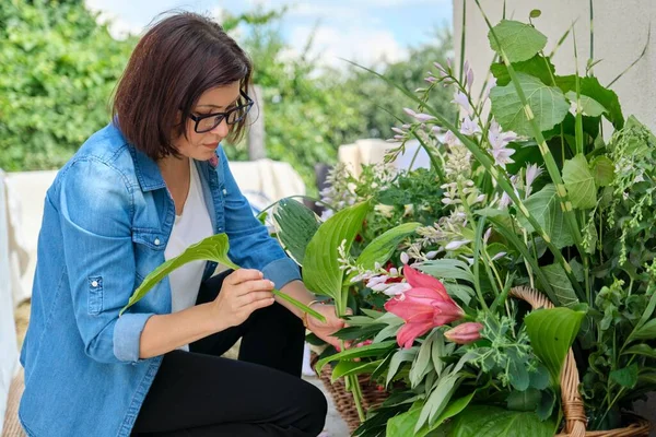 Vrouw bloemist maken bloemstuk in mand outdoor. — Stockfoto