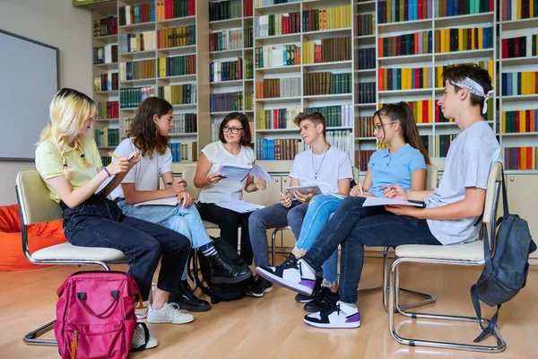 Grupa nastolatków z nauczycielką w średnim wieku w bibliotece — Zdjęcie stockowe
