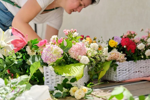 Donna fiorista che fa composizioni floreali in cesto all'aperto. — Foto Stock