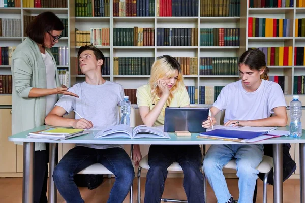 Grupo de estudantes adolescentes estudando em aula de biblioteca com professora mentora — Fotografia de Stock