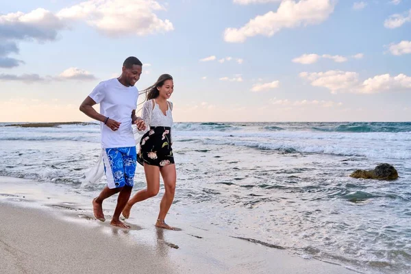 Jong gelukkig paar lopen op het strand hand in hand, kopiëren ruimte — Stockfoto