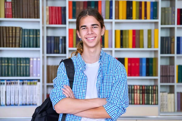 Solo retrato de sonriente confiado estudiante adolescente mirando a la cámara en la biblioteca —  Fotos de Stock