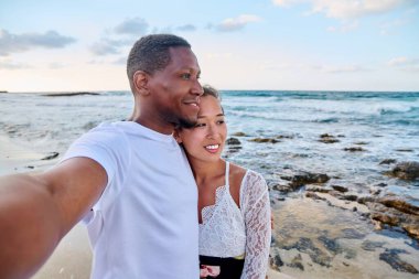 Aşık mutlu çift, sahilde, akıllı telefonda selfie çekiyor.