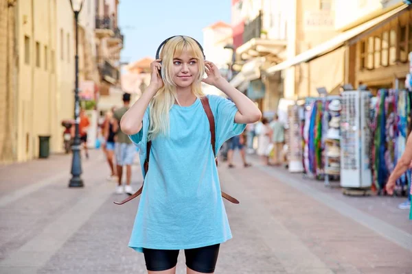 Молода жінка в навушниках з рюкзаком на вулиці туристичного міста — стокове фото