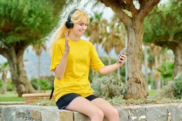 Hipster adolescente dans les écouteurs avec smartphone parler sur lien vidéo — Photo