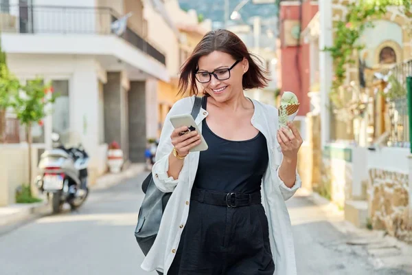 Smiling woman with ice cream walking down the street of summer city — Stock Photo, Image
