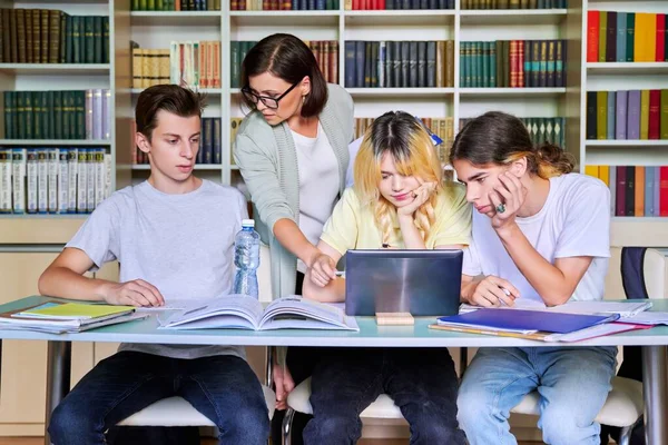 Groep tienerstudenten studeert in bibliotheekklas met vrouwelijke leraar mentor — Stockfoto