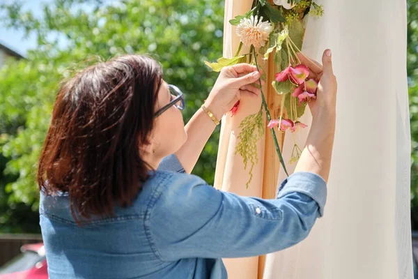 Düğün kemerinde çiçek dekoru yapan kadın.